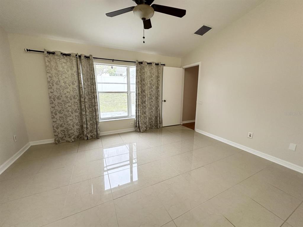 An empty room features light-colored tile flooring, a ceiling fan, and a window with curtains — 931 HUNTER LANE, TARPON SPRINGS, FL