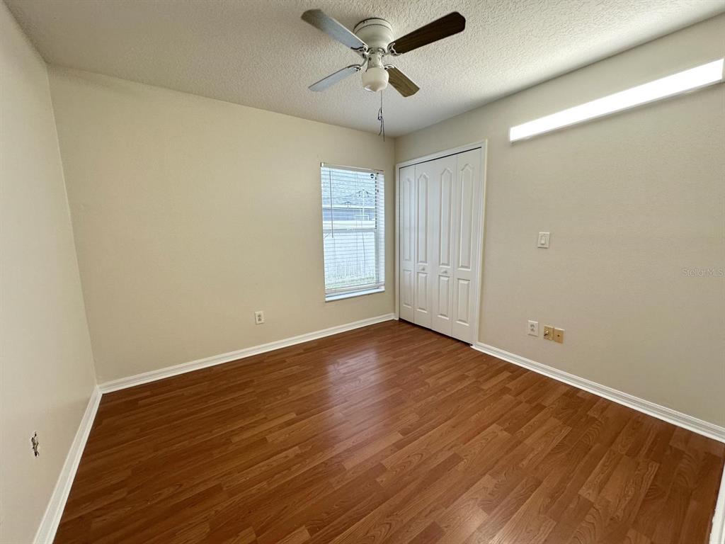 An empty bedroom features wood-look flooring, a ceiling fan, a window, and a closet — 931 HUNTER LANE, TARPON SPRINGS, FL
