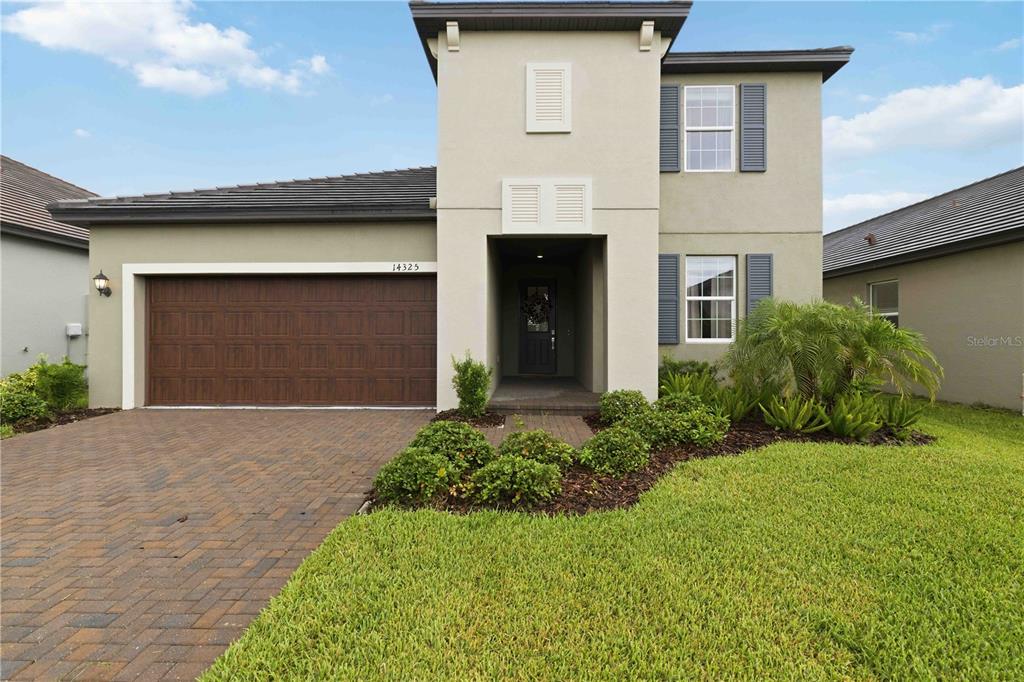A two-story house with a brown garage door, beige stucco exterior, and a paved driveway — 14325 17TH COURT E, PARRISH, FL