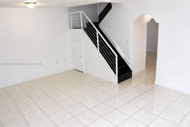 A room with white walls, tiled floors, and a staircase with black steps and railings — 5373 W 24th Ct # 5373, Hialeah FL 33016, HIALEAH, FL