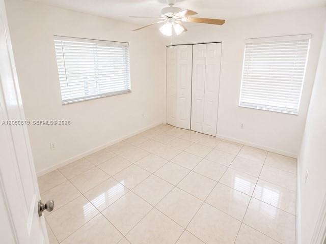 An empty bedroom features white walls, tiled flooring, a ceiling fan, and two windows — 5373 W 24th Ct # 5373, Hialeah FL 33016, HIALEAH, FL