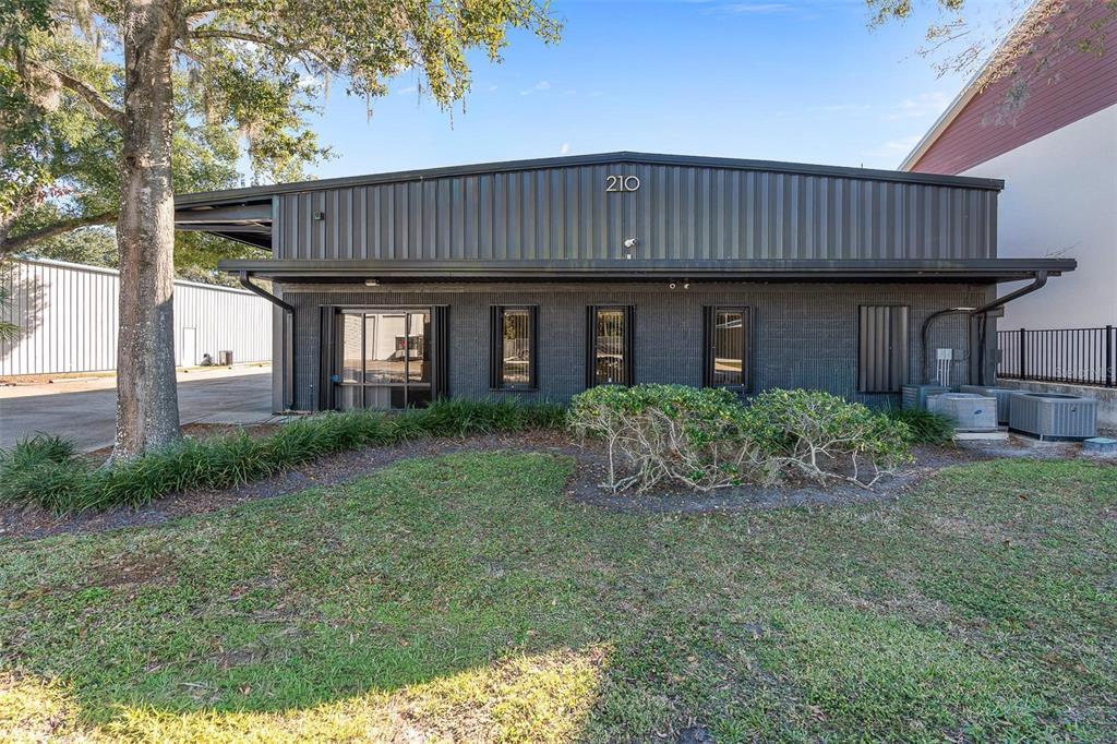 A dark-colored commercial building with a metal roof and a small front lawn — 210 E PALMETTO AVENUE, LONGWOOD, FL