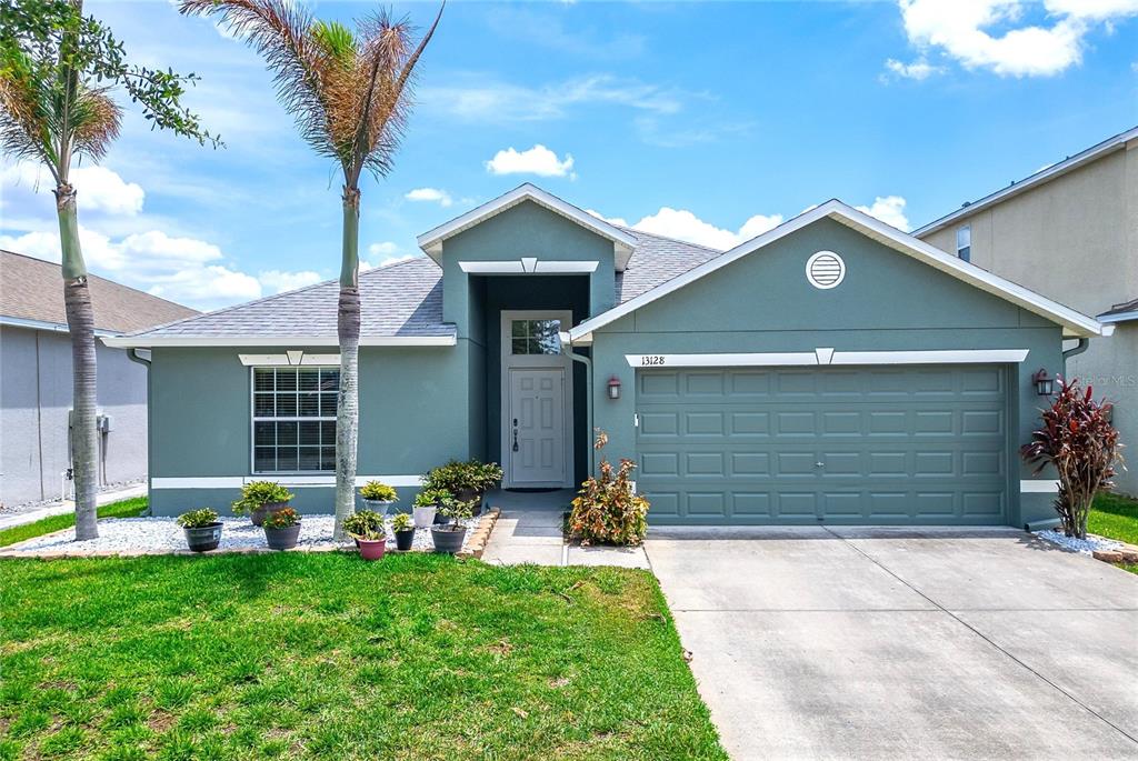A single-story house with a green exterior, a two-car garage, and a palm tree — 13128 ROYAL PINES AVENUE, RIVERVIEW, FL