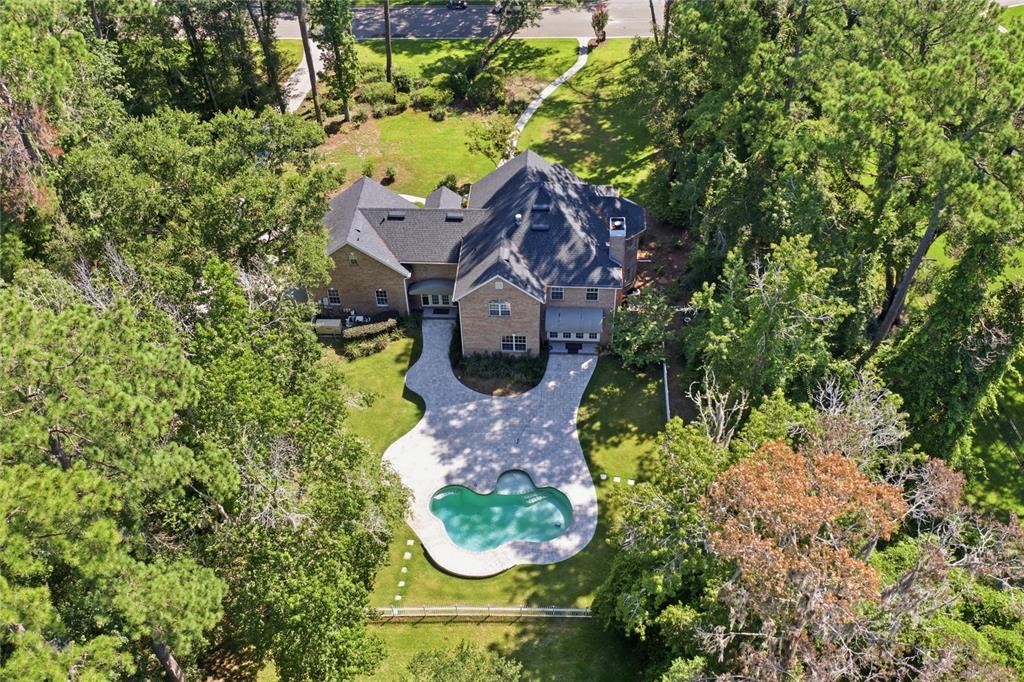 A large two-story brick house with a dark shingled roof sits in a wooded yard — 11121 NW 15TH PLACE, GAINESVILLE, FL