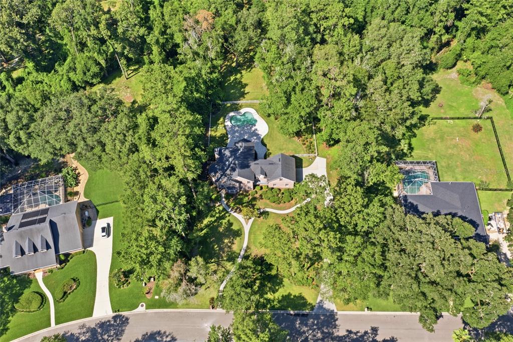 An aerial view shows a house surrounded by dense trees with a red property boundary — 11121 NW 15TH PLACE, GAINESVILLE, FL
