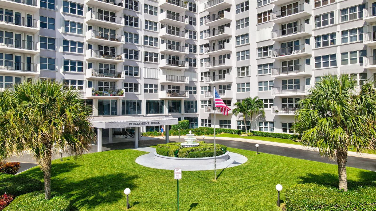 Exterior view of a multi-story apartment building with a circular driveway and a central fountain — 405 N Ocean Boulevard # 329, Pompano Beach FL 33062, POMPANO BEACH, FL