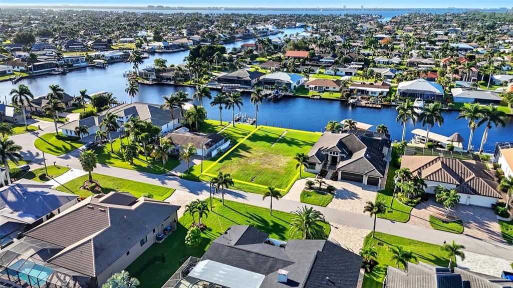 An aerial view shows a vacant waterfront lot situated between two residential homes — 126 SW 50TH STREET, CAPE CORAL, FL