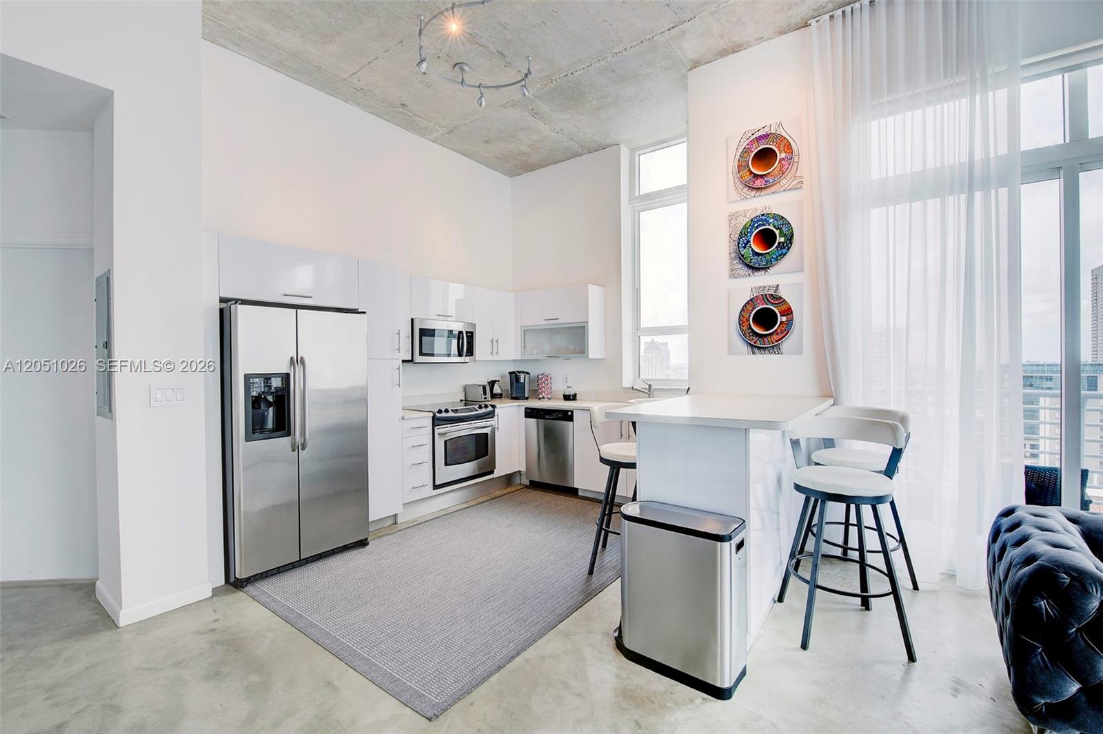 A modern kitchen features white cabinetry, stainless steel appliances, and a concrete ceiling — 234 NE 3rd St, Miami FL 33132, MIAMI, FL