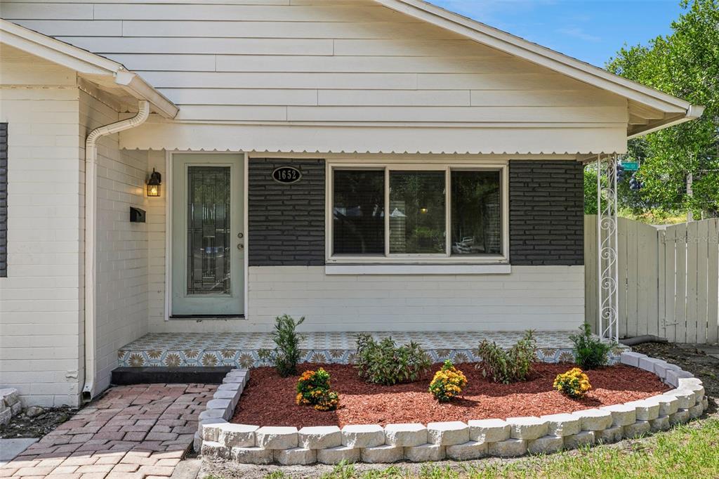 The exterior of a house features a light-colored brick facade, a dark accent wall, and landscaping — 1652 BERKSHIRE AVENUE, WINTER PARK, FL