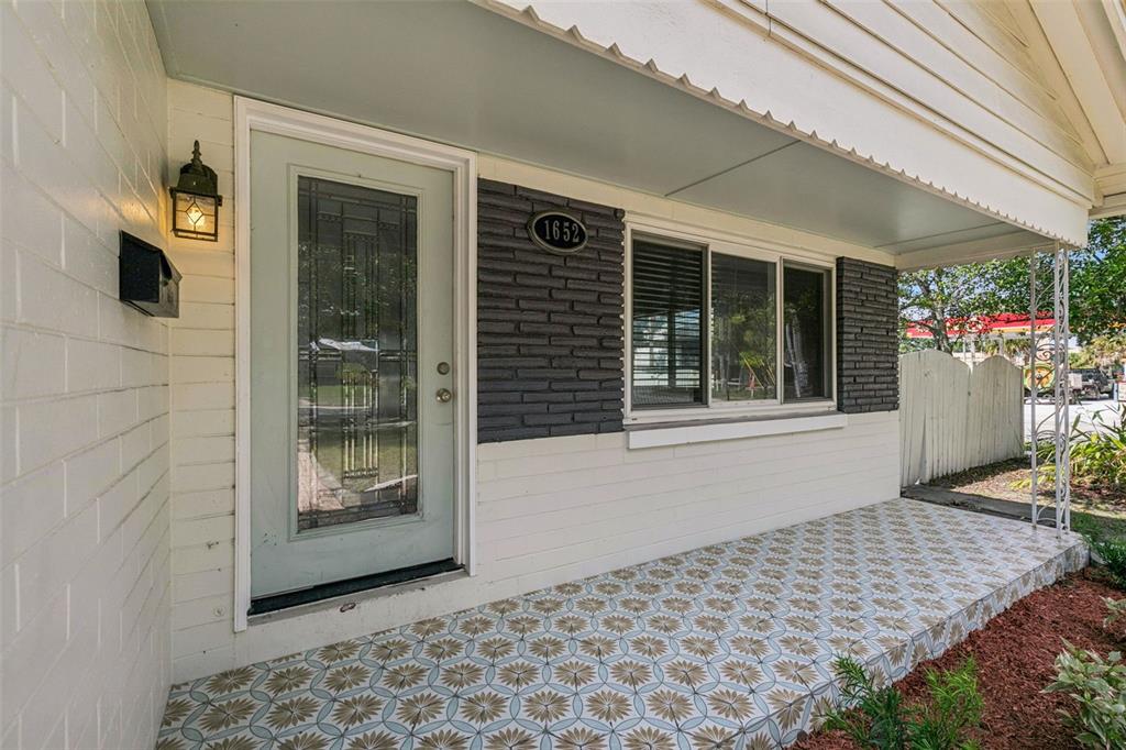 A front porch with patterned tile flooring, a light green front door, and dark brick accents — 1652 BERKSHIRE AVENUE, WINTER PARK, FL