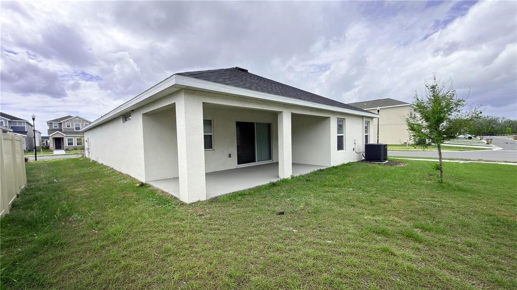 The exterior view shows the back of a single-story house with a covered concrete patio — 485 WINDY WILLOW WAY, ST CLOUD, FL