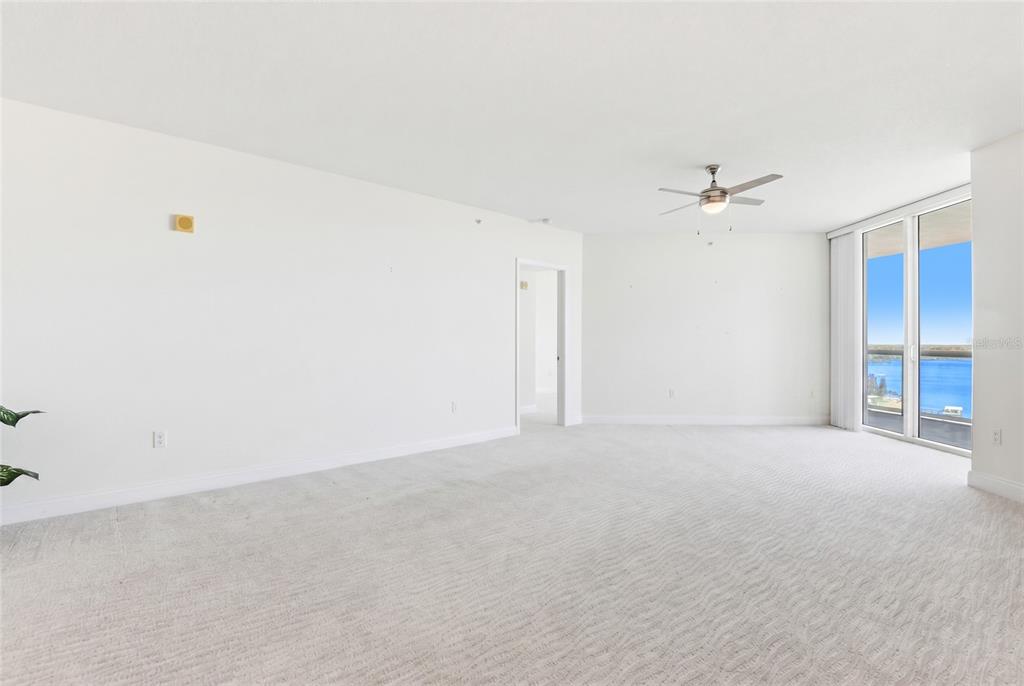 An empty living room with white walls, carpeted flooring, a ceiling fan, and a balcony view — 241 RIVERSIDE DRIVE UNIT 1604, HOLLY HILL, FL
