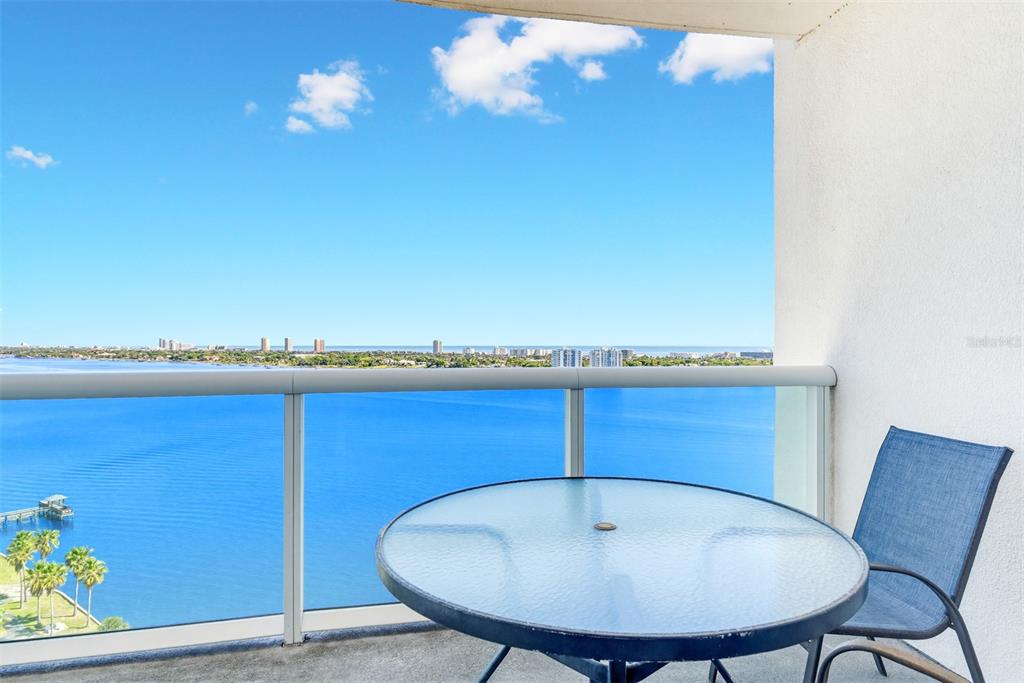 A balcony features a glass-topped table, a blue chair, and a view of the water — 241 RIVERSIDE DRIVE UNIT 1604, HOLLY HILL, FL