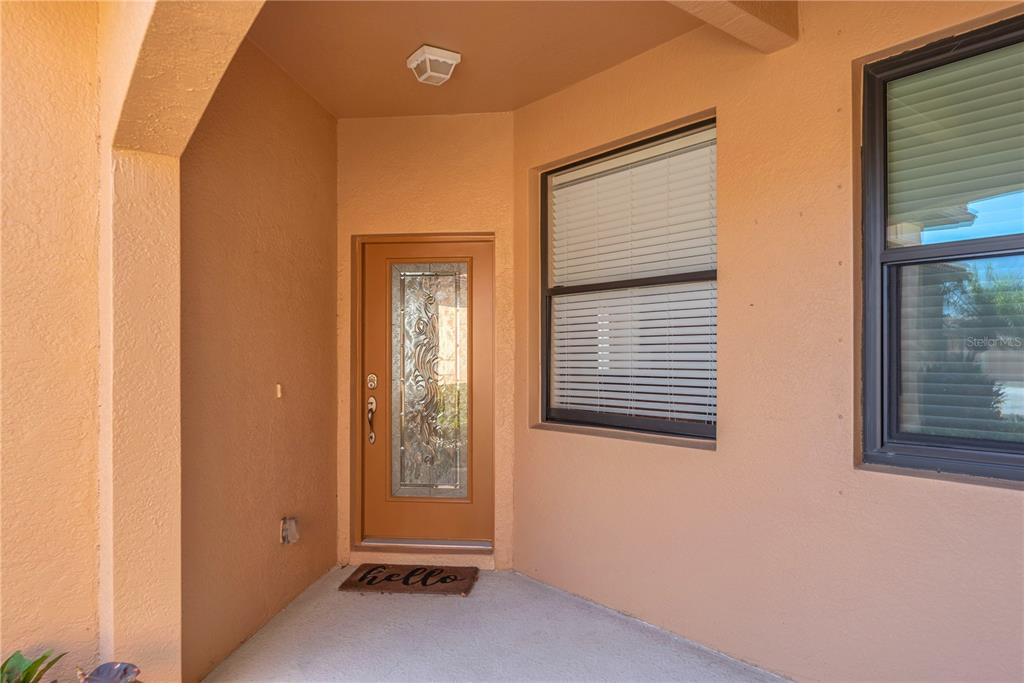 A covered entryway features a tan exterior, a glass-paneled door, and a welcome mat — 107 SHELL FALLS DRIVE, APOLLO BEACH, FL