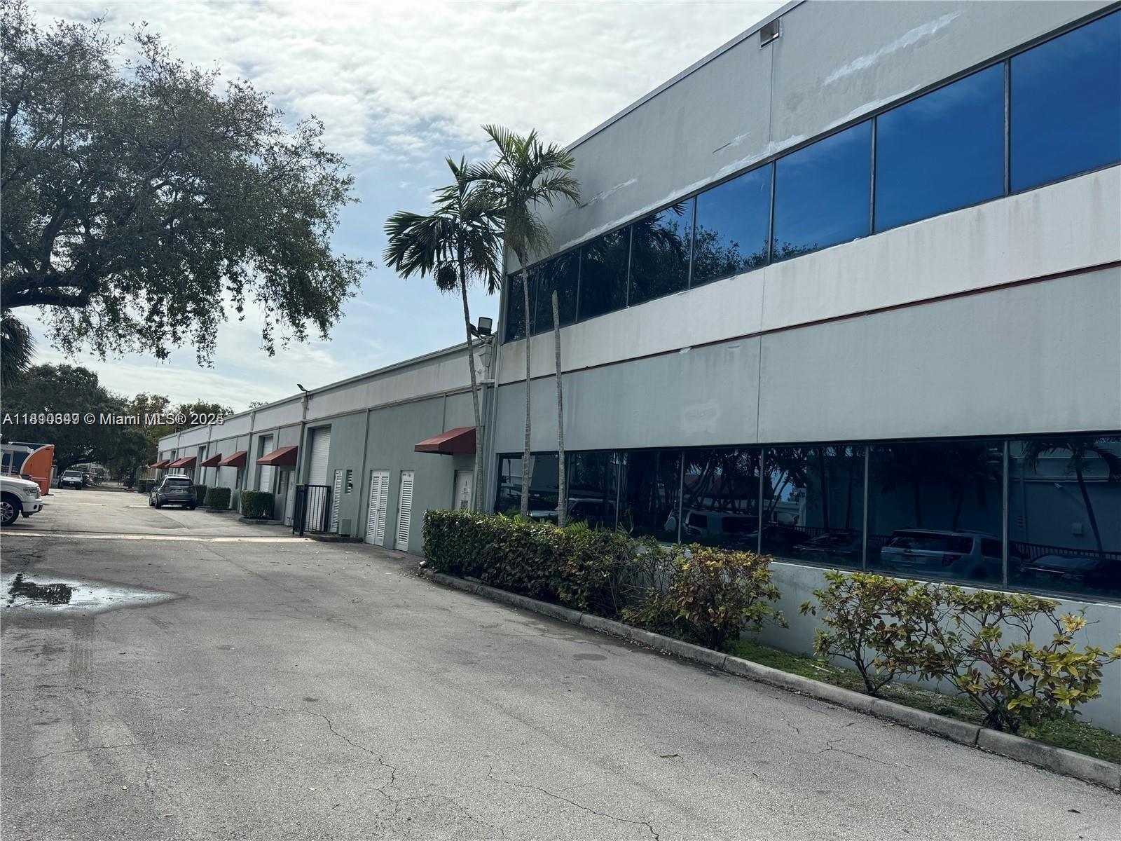 A low-rise commercial building features a gray facade, large reflective windows, and small red awnings — 2870 Stirling Rd, Hollywood FL 33020, HOLLYWOOD, FL