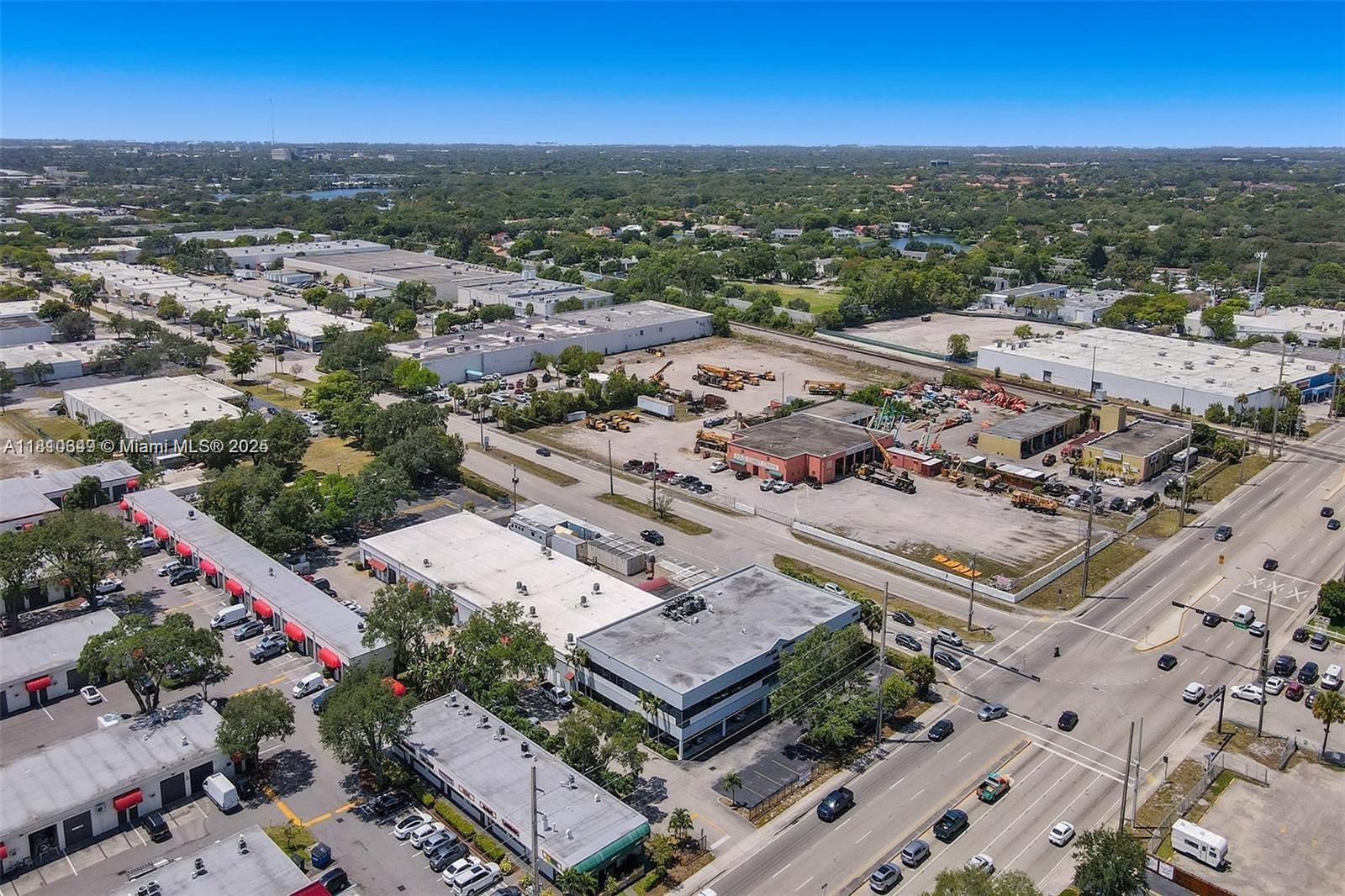 An aerial view shows industrial buildings, a large parking lot with heavy equipment, and roads — 2870 Stirling Rd, Hollywood FL 33020, HOLLYWOOD, FL