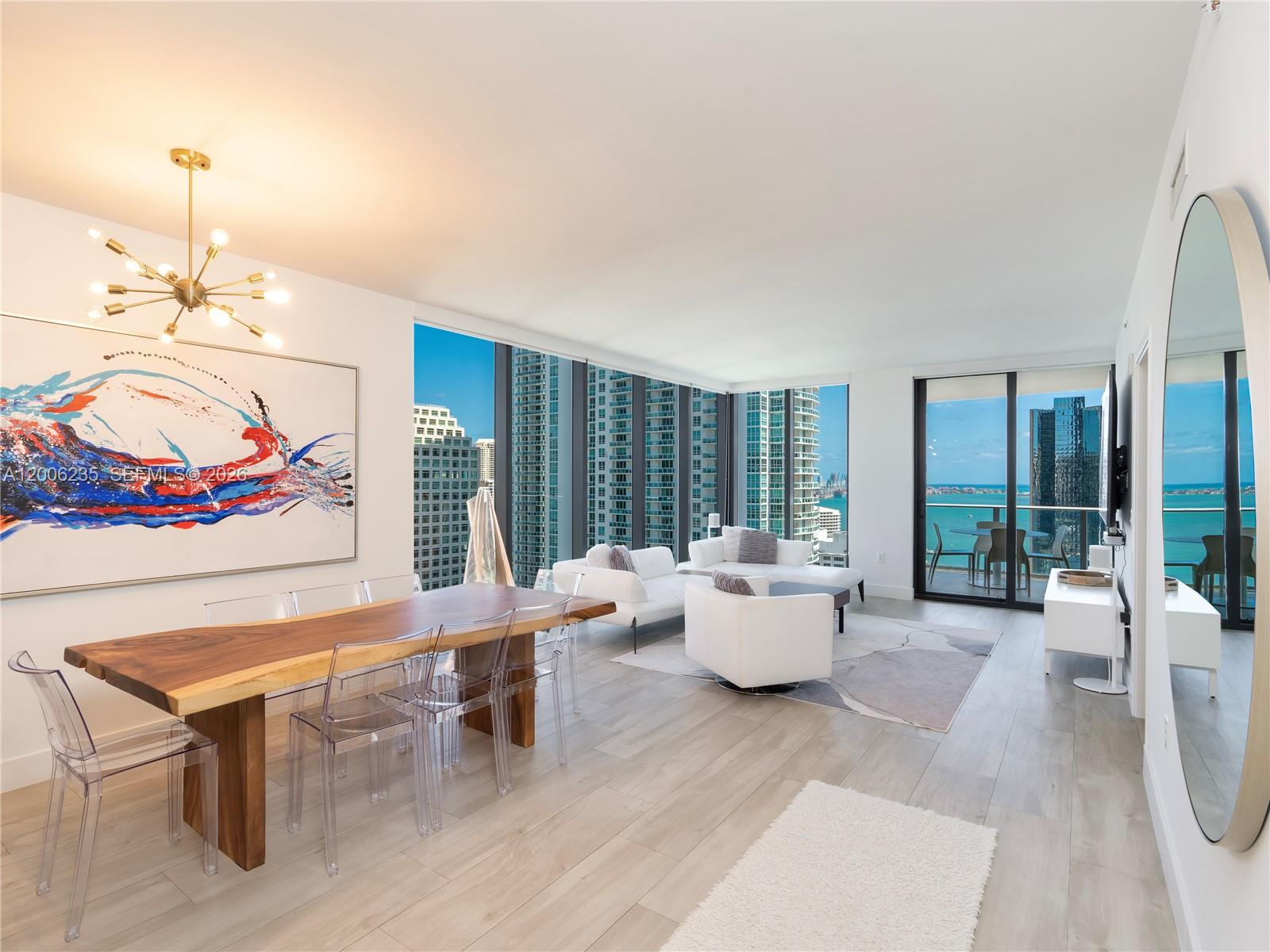 A modern living and dining area features a live-edge table, floor-to-ceiling windows, and ocean views — 1010 Brickell Ave # 2801, Miami FL 33131, MIAMI, FL