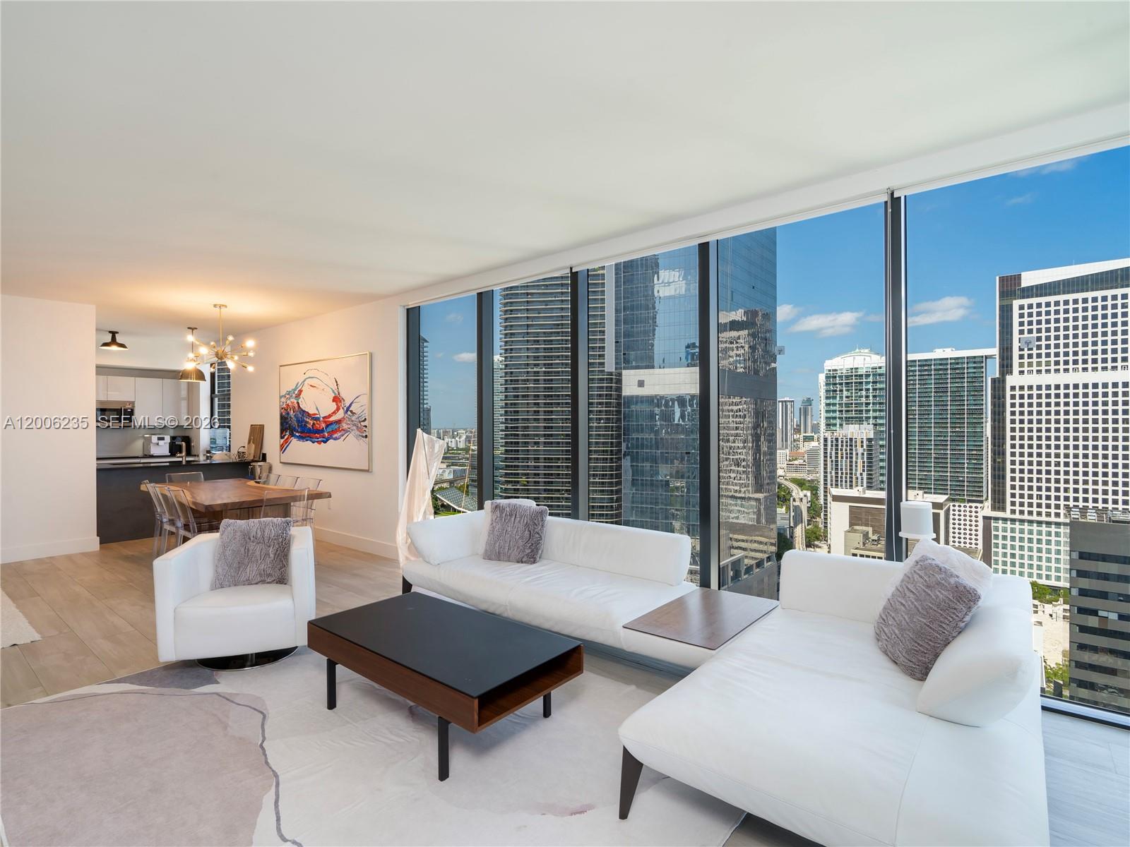 A modern living room with white furniture and floor-to-ceiling windows overlooking a city skyline — 1010 Brickell Ave # 2801, Miami FL 33131, MIAMI, FL