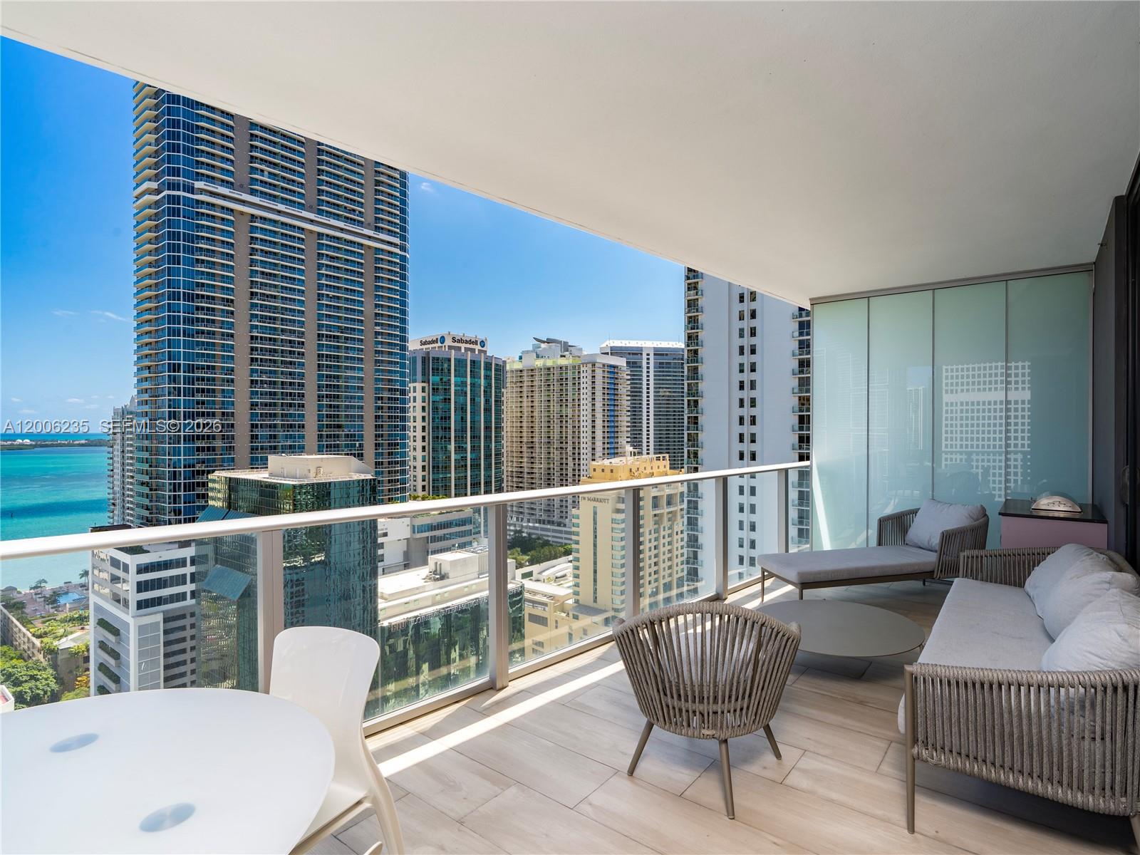 A balcony with outdoor furniture overlooks a city skyline and a body of water — 1010 Brickell Ave # 2801, Miami FL 33131, MIAMI, FL