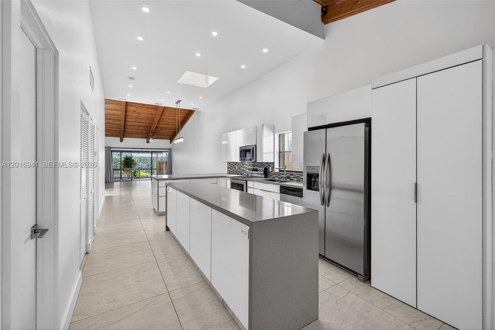 A modern kitchen features white cabinetry, gray countertops, and a vaulted wood-paneled ceiling — 2619 S Parkview Dr, Hallandale Beach FL 33009, HALLANDALE BEACH, FL