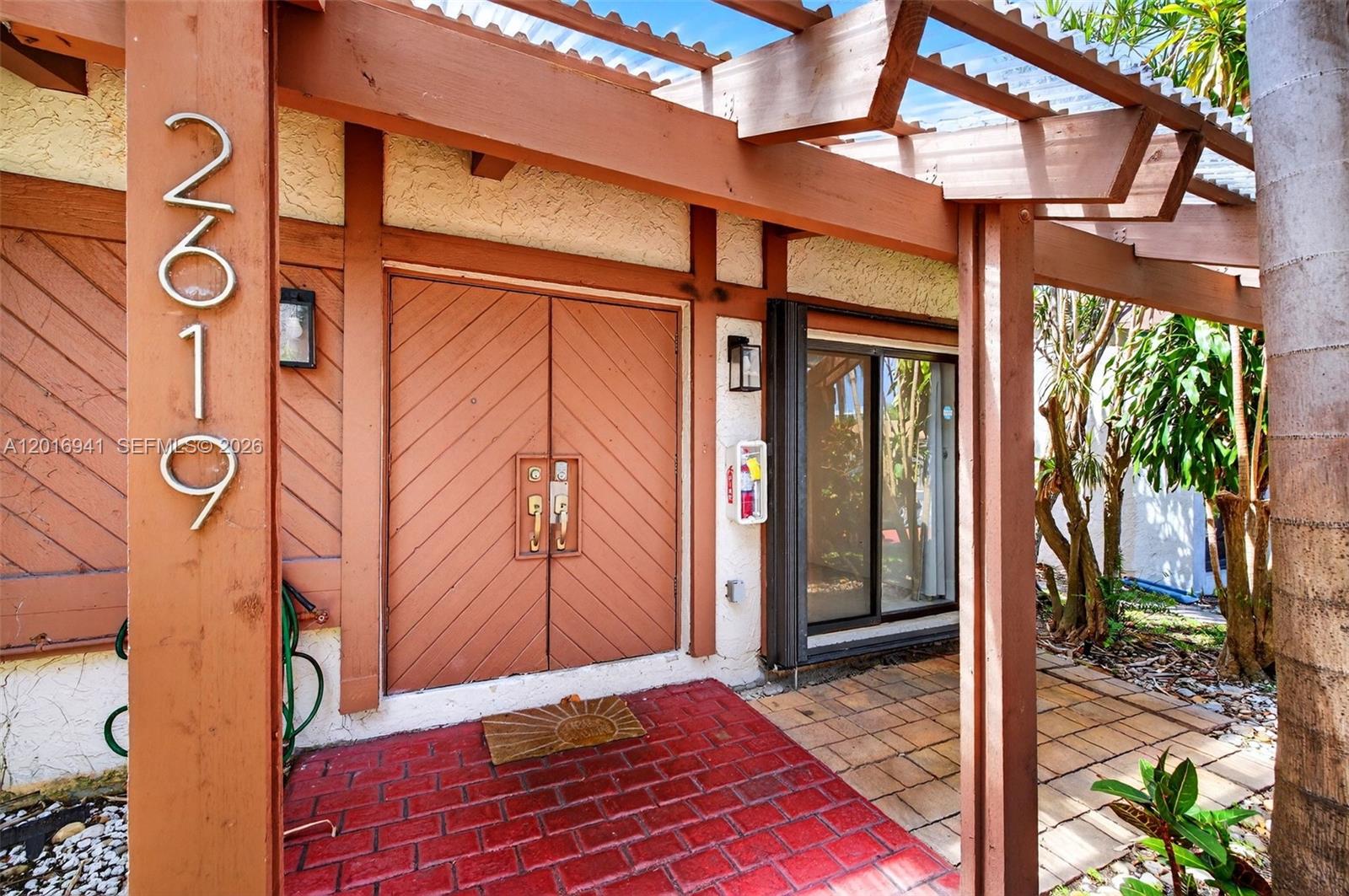 The exterior entrance features a red brick walkway, double wooden doors, and a wooden pergola — 2619 S Parkview Dr, Hallandale Beach FL 33009, HALLANDALE BEACH, FL