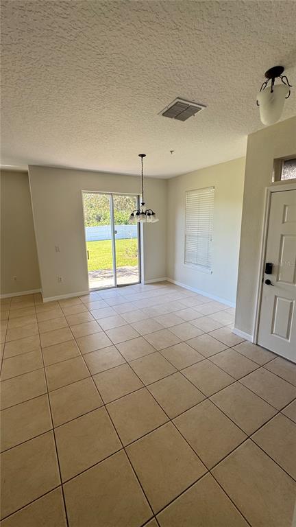 A room with beige tile flooring, a sliding glass door, and a hanging light fixture — 6410 S GOLDENROD ROAD, ORLANDO, FL