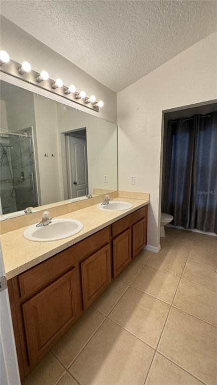 A bathroom features a double vanity with wood cabinets, a large mirror, and tiled flooring — 6410 S GOLDENROD ROAD, ORLANDO, FL