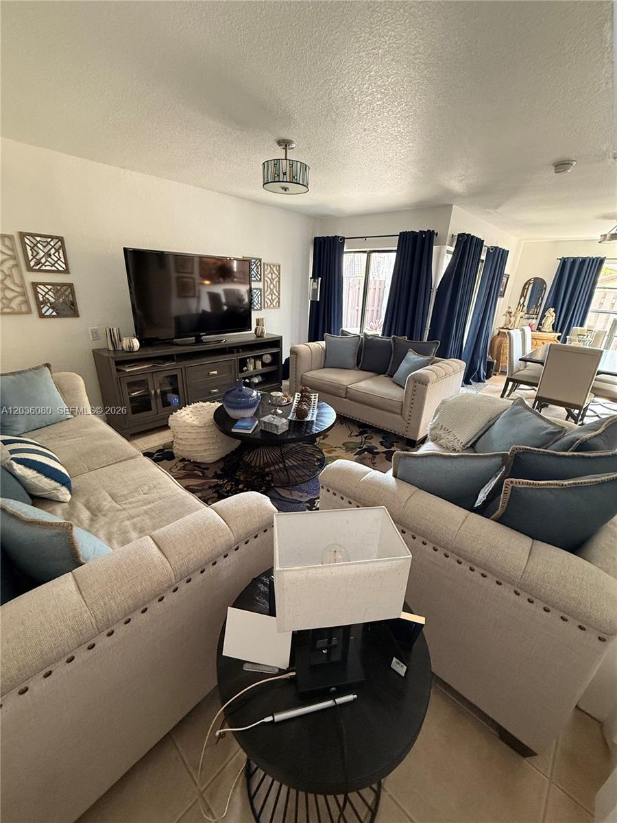 This living room features beige tufted sofas, a dark wood coffee table, and blue curtains — 11332 SW 133rd Ct # 2, Miami FL 33186, MIAMI, FL