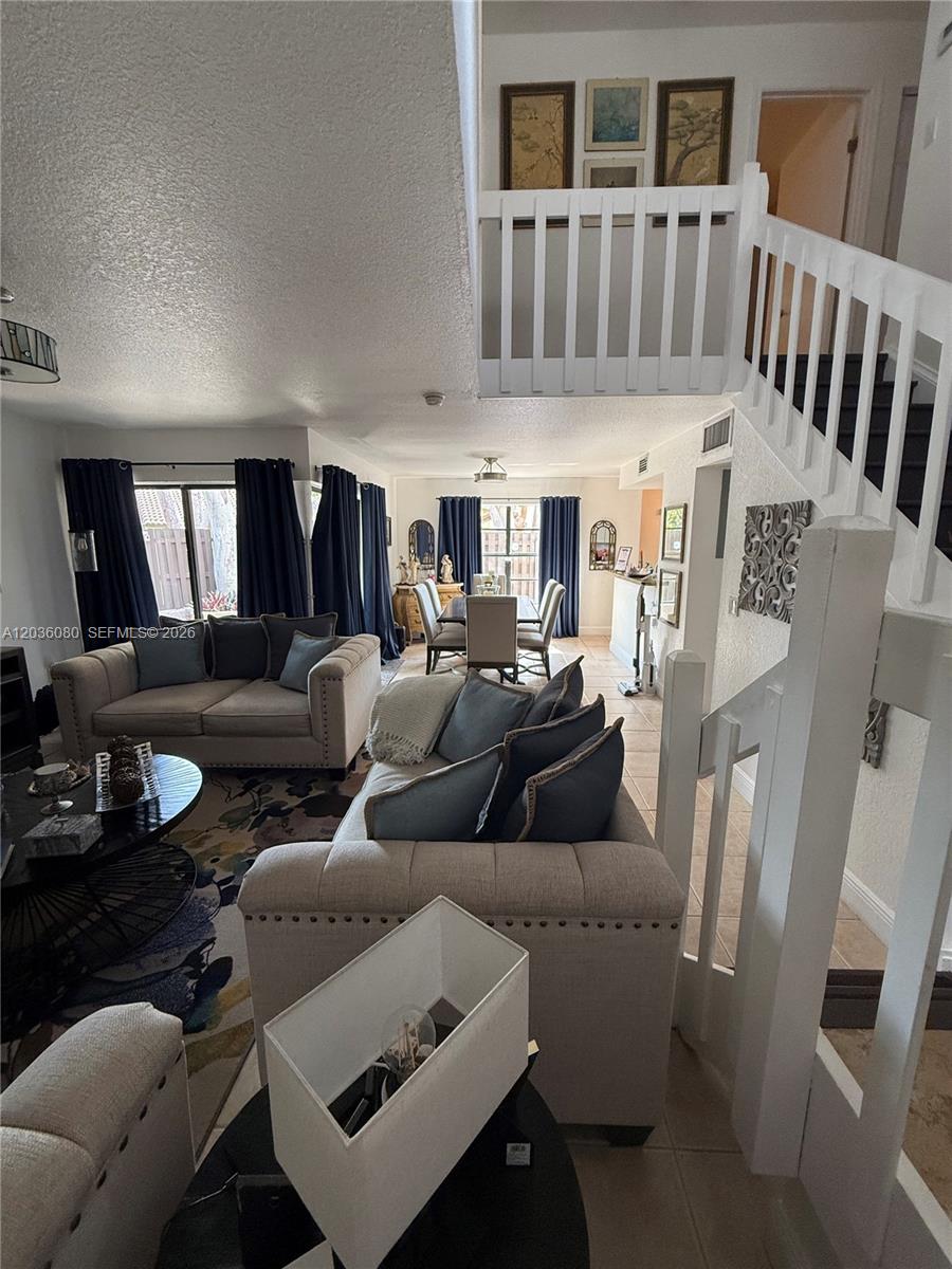 A living room with beige sofas and a dining area features a staircase with white railings — 11332 SW 133rd Ct # 2, Miami FL 33186, MIAMI, FL