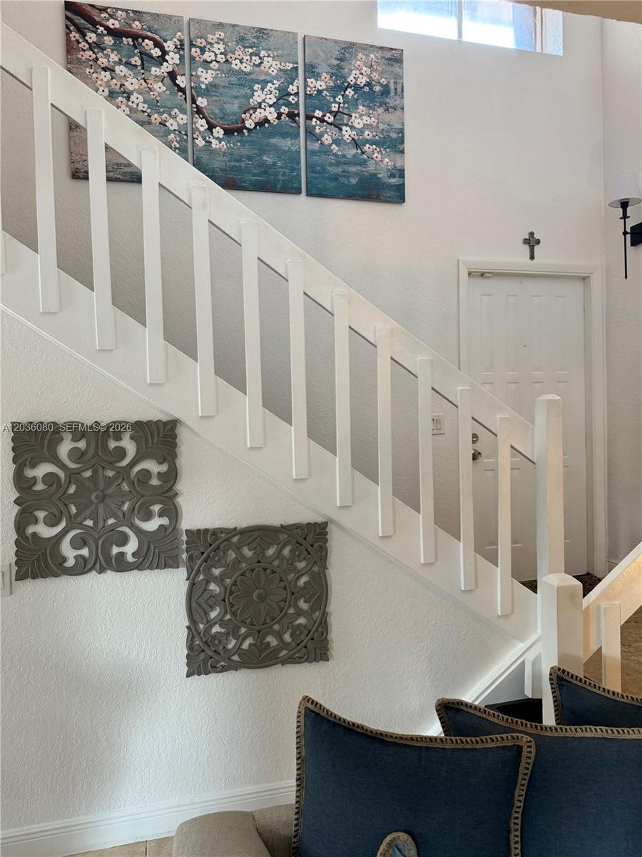 A staircase with white railings features wall art and a door in a residential interior — 11332 SW 133rd Ct # 2, Miami FL 33186, MIAMI, FL