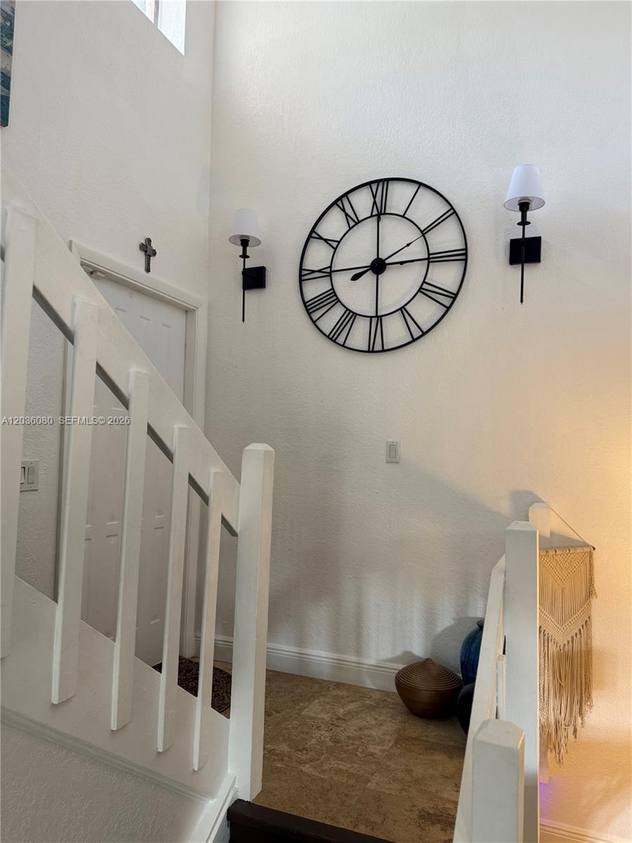 A staircase with white railings leads to a landing featuring a large wall clock — 11332 SW 133rd Ct # 2, Miami FL 33186, MIAMI, FL