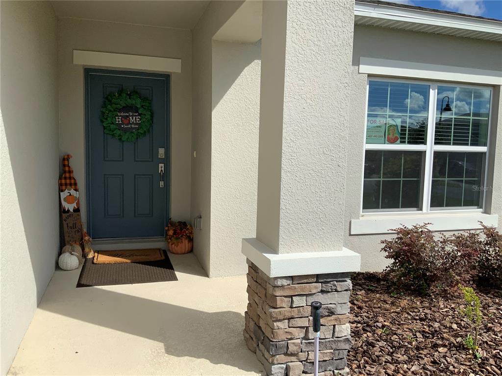 A front porch with a blue door, stone-based pillar, and fall decorations — 5639 COSTA BLANCA WAY, DAVENPORT, FL