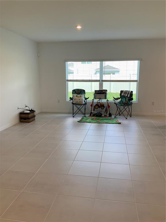 A spacious room with light-colored tile flooring, white walls, and a large window — 5639 COSTA BLANCA WAY, DAVENPORT, FL