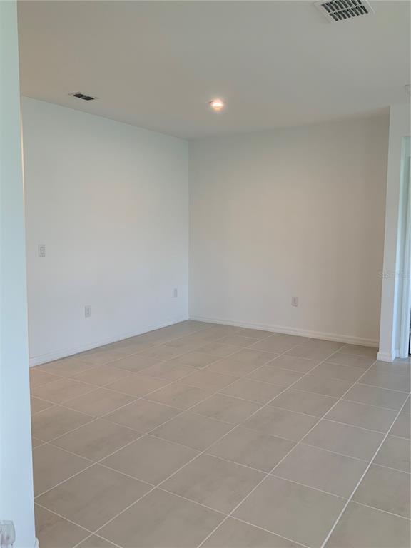 An empty room features white walls, light-colored tile flooring, and a single recessed ceiling light — 5639 COSTA BLANCA WAY, DAVENPORT, FL