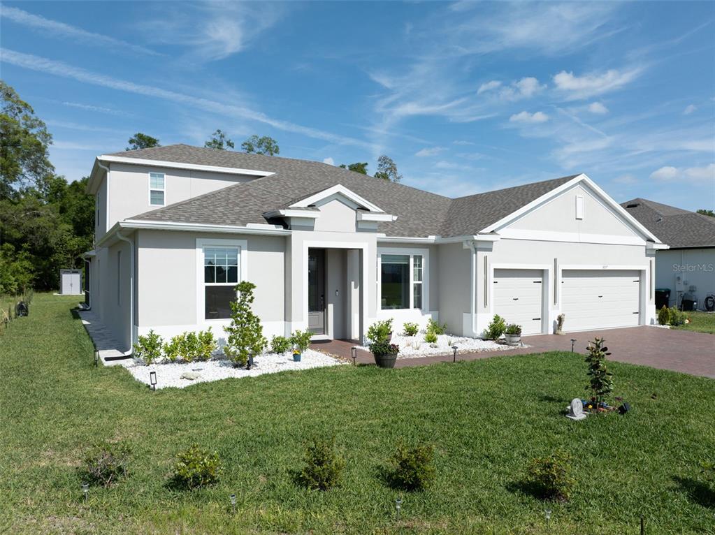 A light-colored single-story house with a two-car garage and a landscaped front yard — 5897 SIERRA CROWN STREET, MOUNT DORA, FL