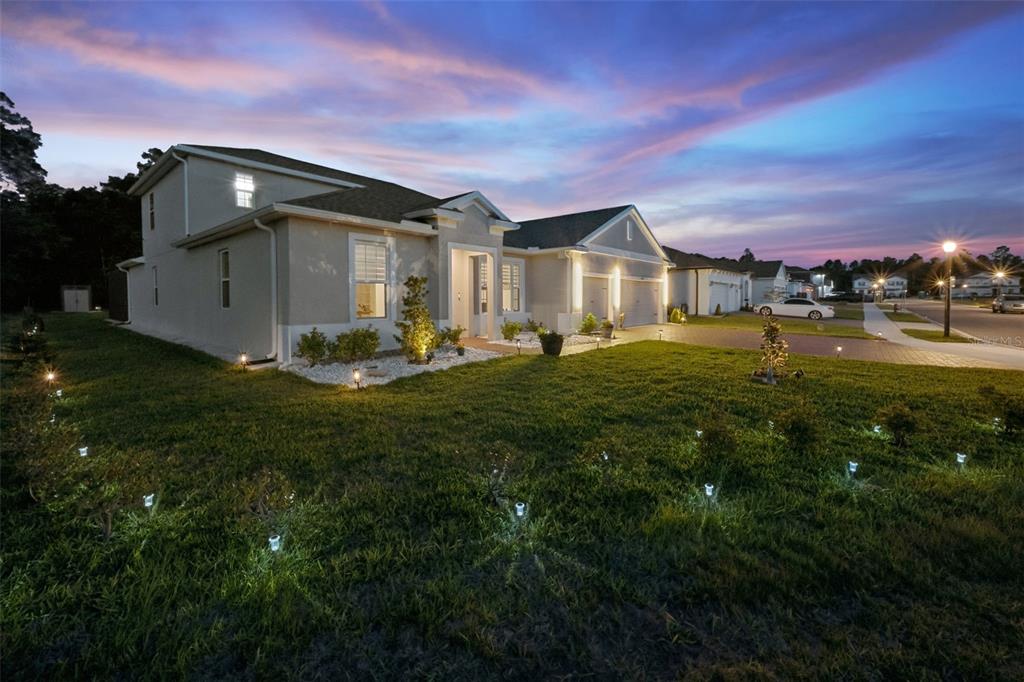A two-story suburban house with a paved driveway and landscape lighting at dusk — 5897 SIERRA CROWN STREET, MOUNT DORA, FL