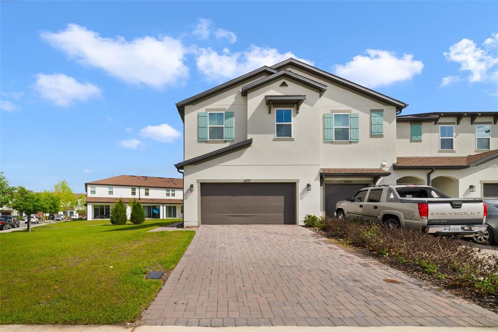 A two-story townhouse with a paved driveway and a two-car garage under a blue sky — 4371 CREEK COVE LANE, KISSIMMEE, FL