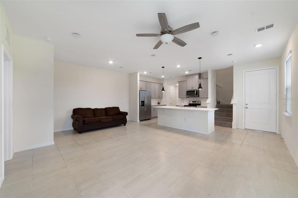 An open-concept living area features a brown sofa, a kitchen island, and light tile flooring — 4371 CREEK COVE LANE, KISSIMMEE, FL