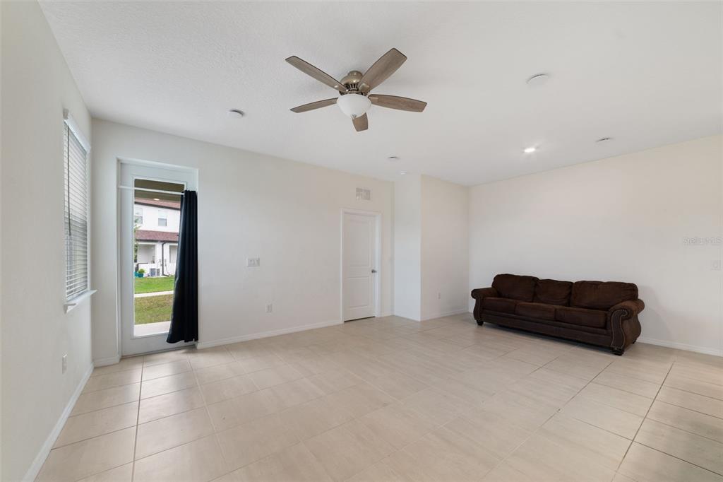 A living room with light tile flooring, a ceiling fan, and a brown sofa — 4371 CREEK COVE LANE, KISSIMMEE, FL