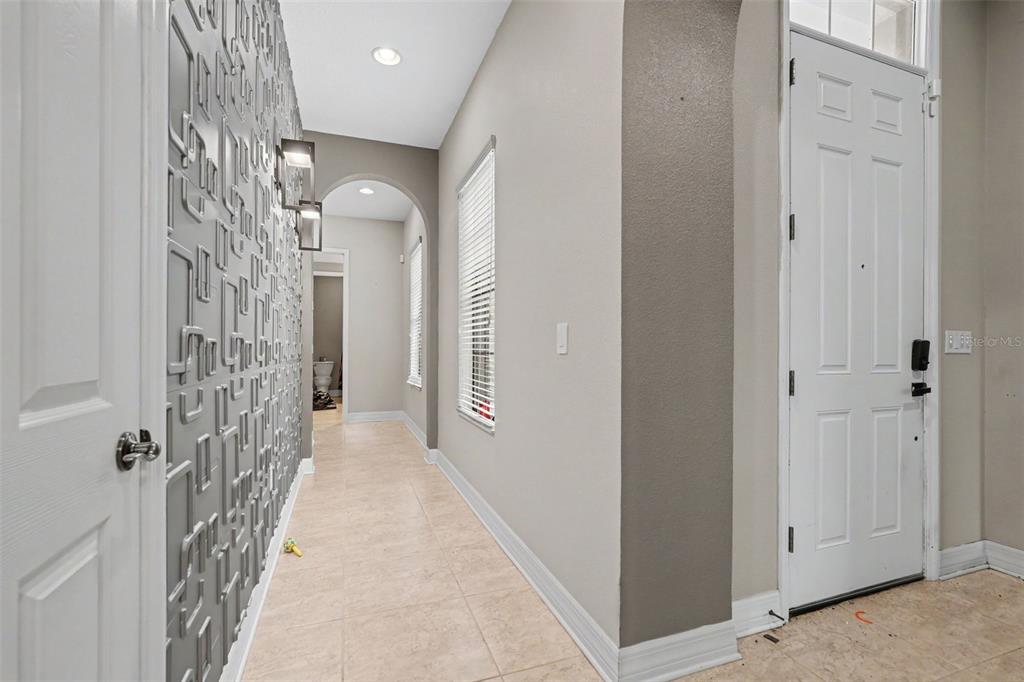 A tiled entryway features a textured accent wall, an arched hallway, and a white front door — 31957 MARDELLE PLACE, WESLEY CHAPEL, FL