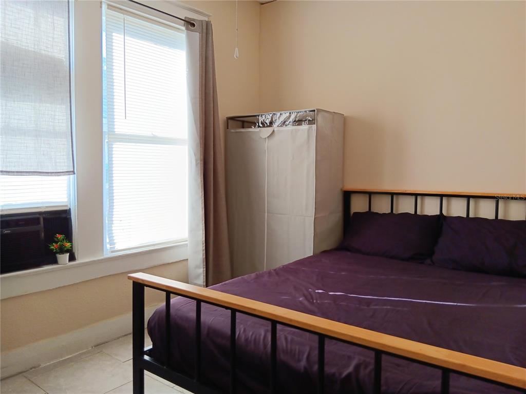 A bedroom features a metal-framed bed with purple bedding and a portable fabric wardrobe — 3508 E 28TH AVENUE, TAMPA, FL