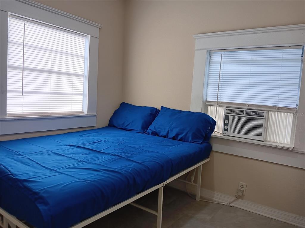 A bedroom features a bed with blue bedding, two windows, and a window air conditioner — 3508 E 28TH AVENUE, TAMPA, FL