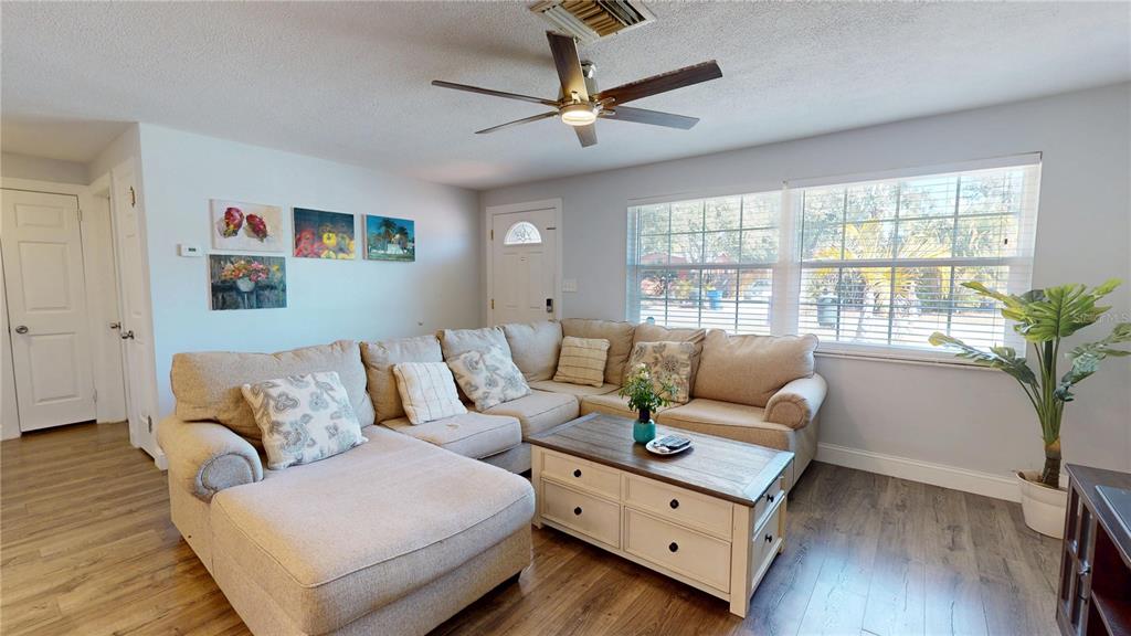 A living room features a beige sectional sofa, a coffee table, and wood-look flooring — 2020 YALE AVENUE, DUNEDIN, FL