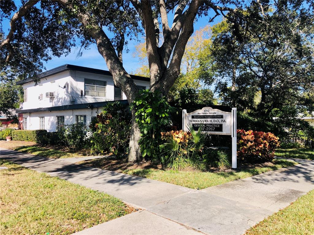 A two-story white building sits behind a sign for a medical practice and trees — 1762 N FORT HARRISON AVENUE, CLEARWATER, FL