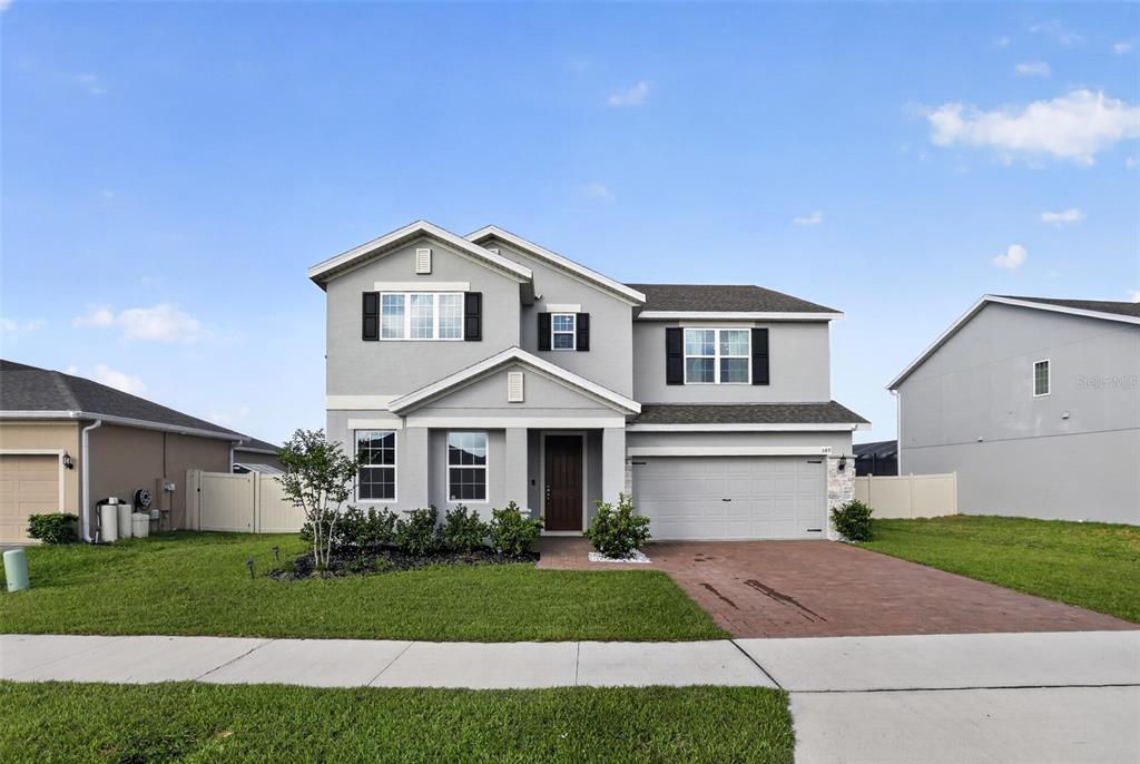 A two-story gray house with a two-car garage and a paved driveway — 589 JUPITER BEACH ROAD, GROVELAND, FL