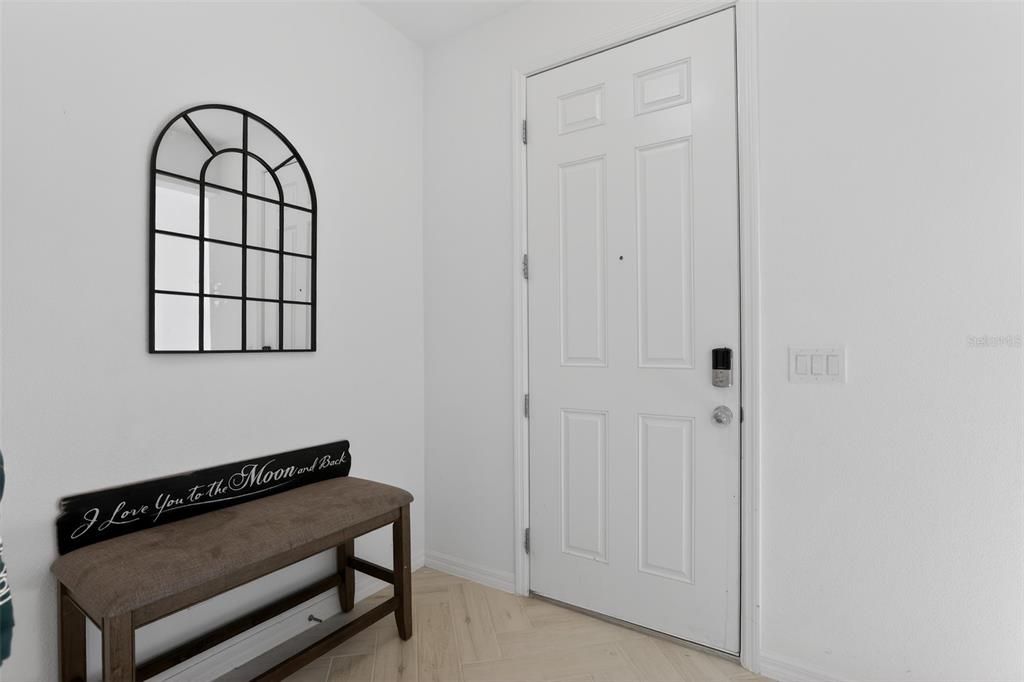 An entryway features a white door, a wooden bench with a sign, and a wall mirror — 589 JUPITER BEACH ROAD, GROVELAND, FL