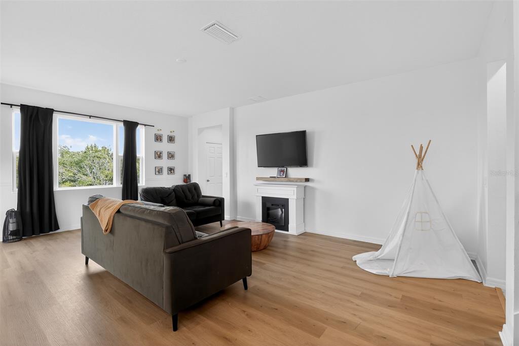 A living room features light wood flooring, a fireplace with a television, and a teepee — 589 JUPITER BEACH ROAD, GROVELAND, FL