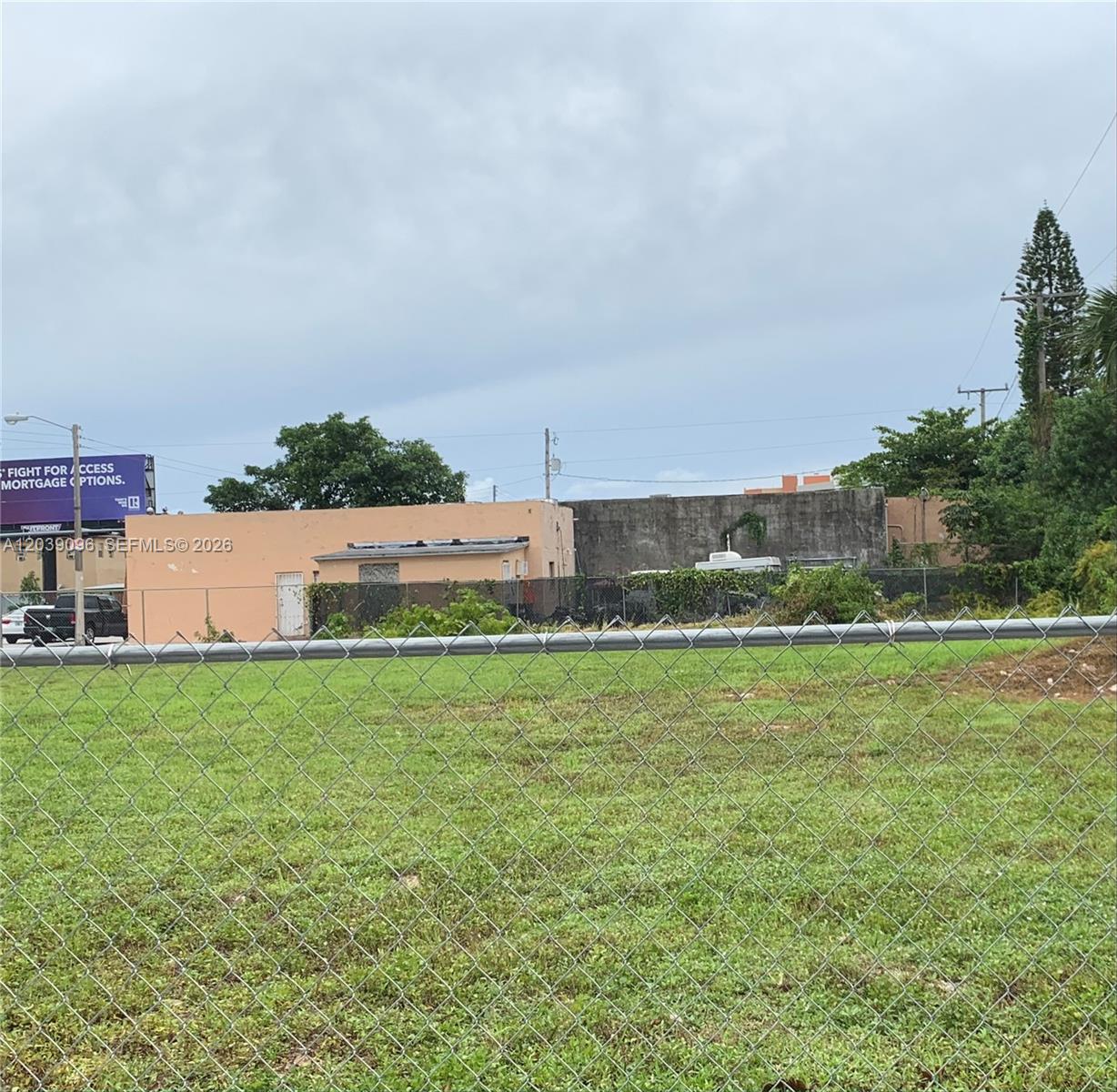 A chain-link fence encloses a grassy lot in front of a low-rise commercial building — 4923 NW 17th Ave, Miami FL 33142, MIAMI, FL
