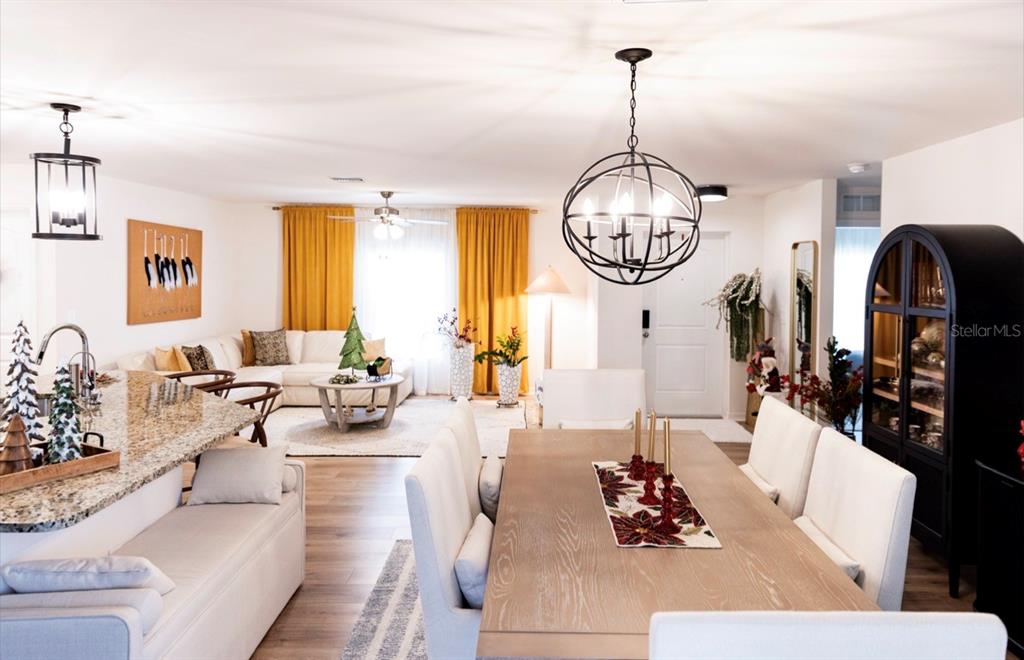 An open-concept living and dining area features a kitchen island, white furniture, and yellow curtains — 1660 LANSDALE AVENUE, NORTH PORT, FL