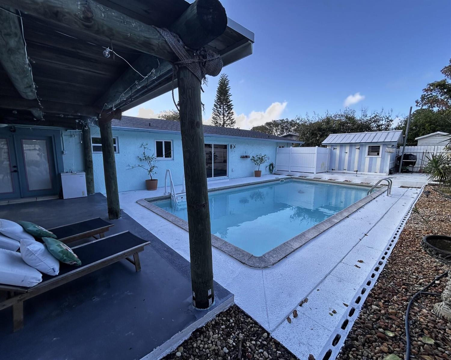 A backyard features a swimming pool, a covered patio with lounge chairs, and a shed — 1301 SE Sandpiper Lane, Stuart FL 34996, STUART, FL